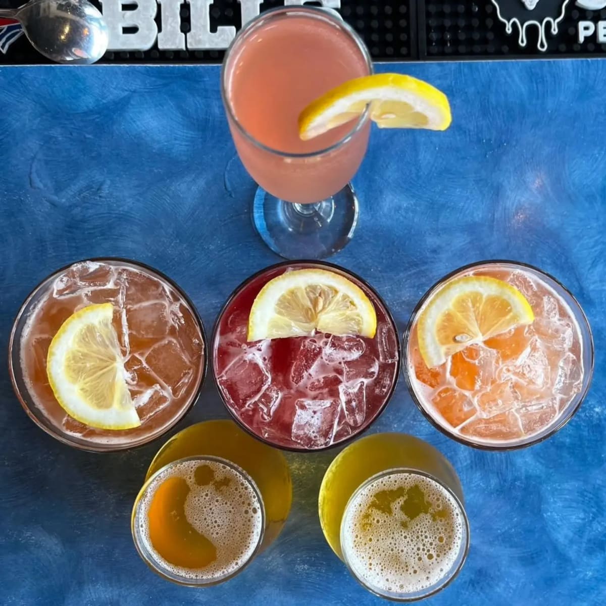 Five cocktails in different glasses seen from above on the blue table