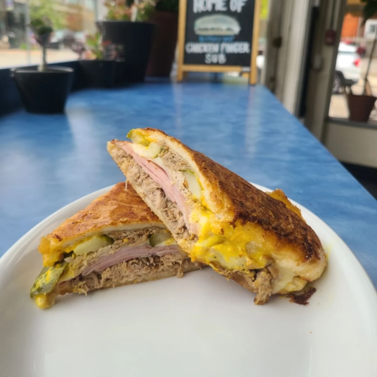 A pressed Cuban sandwich cut in half on a white plate