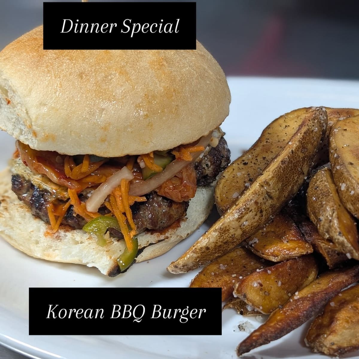 Korean BBQ burger with pickled vegetables on a hard roll, potato wedges beside it