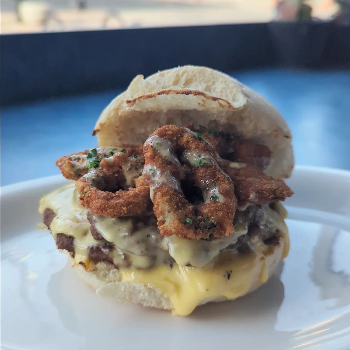 A smash burger with melted cheese and crispy fried onions on a soft roll