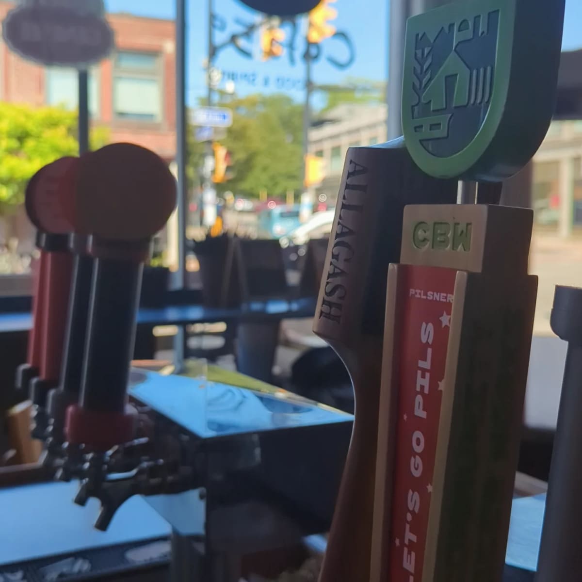 The tap handles at the bar with Allen Street in the window behind them